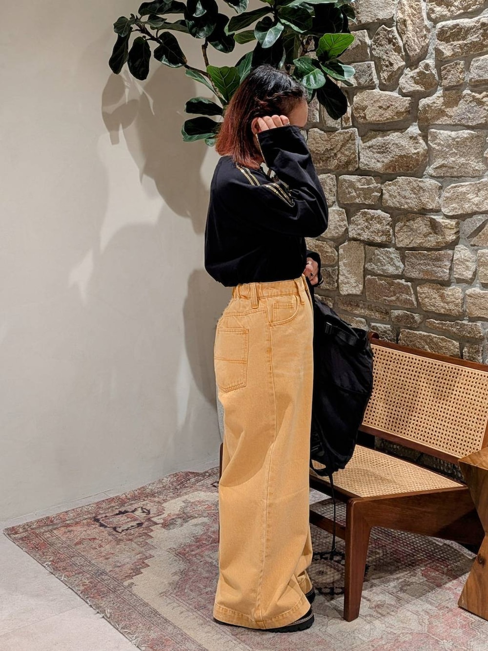 ブラック系のバックパック/リュック、ブラック系のローファー、オレンジ系のデニムパンツを着用したレディースの冬コーディネートの2枚目の写真