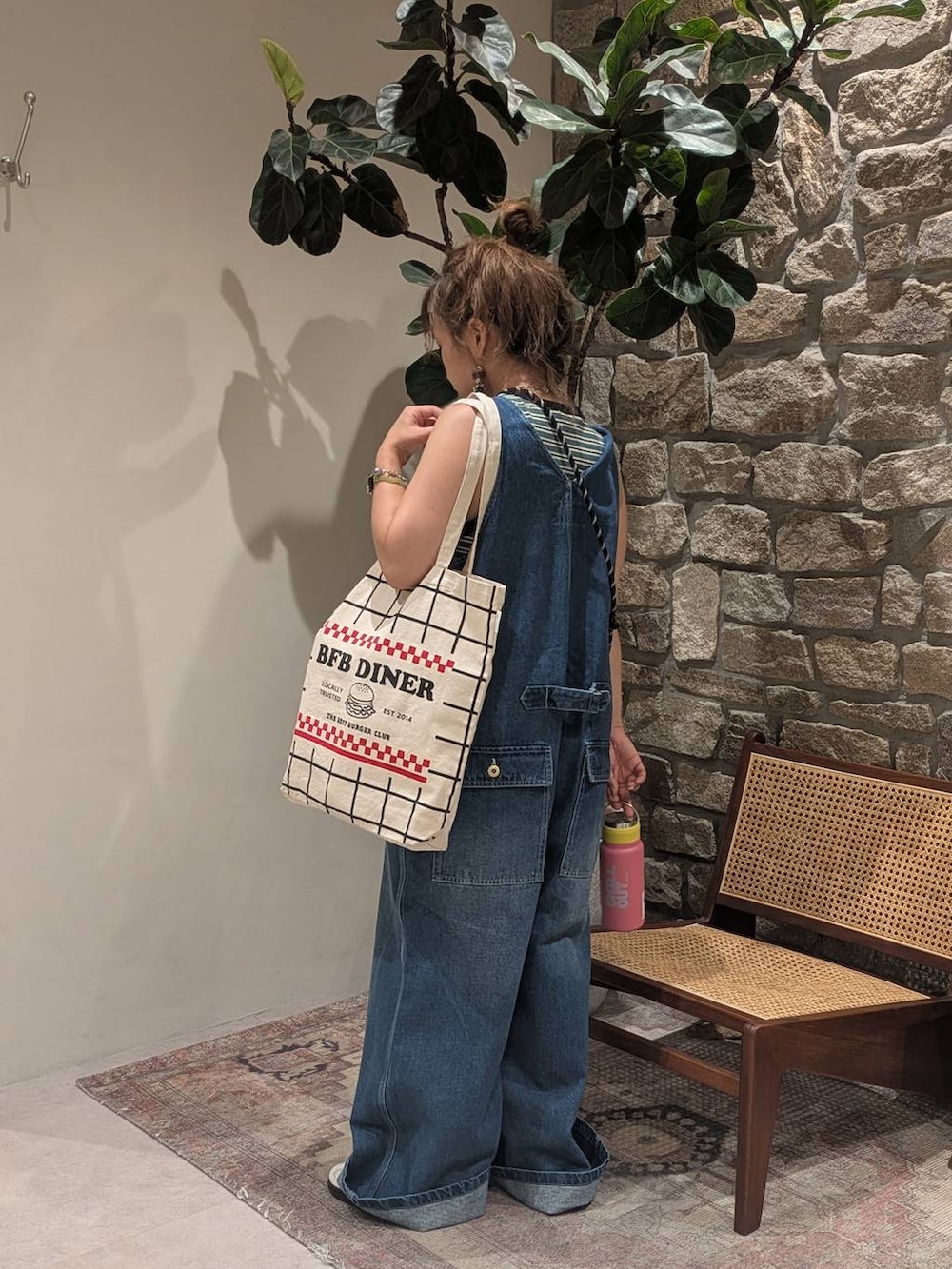 ブラック系のトートバッグ、ベージュ系のスニーカー、グリーン系のTシャツ/カットソーを着用したレディースの夏コーディネートの3枚目の写真