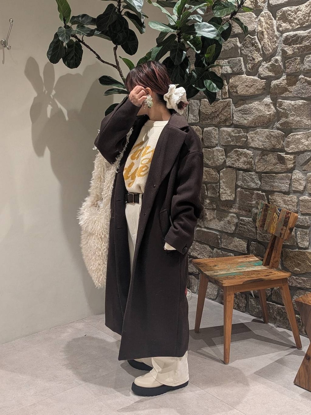 ブラウン系のチェスターコート、ベージュ系のブーツ、ベージュ系のショルダーバッグを着用したレディースの冬コーディネートの3枚目の写真