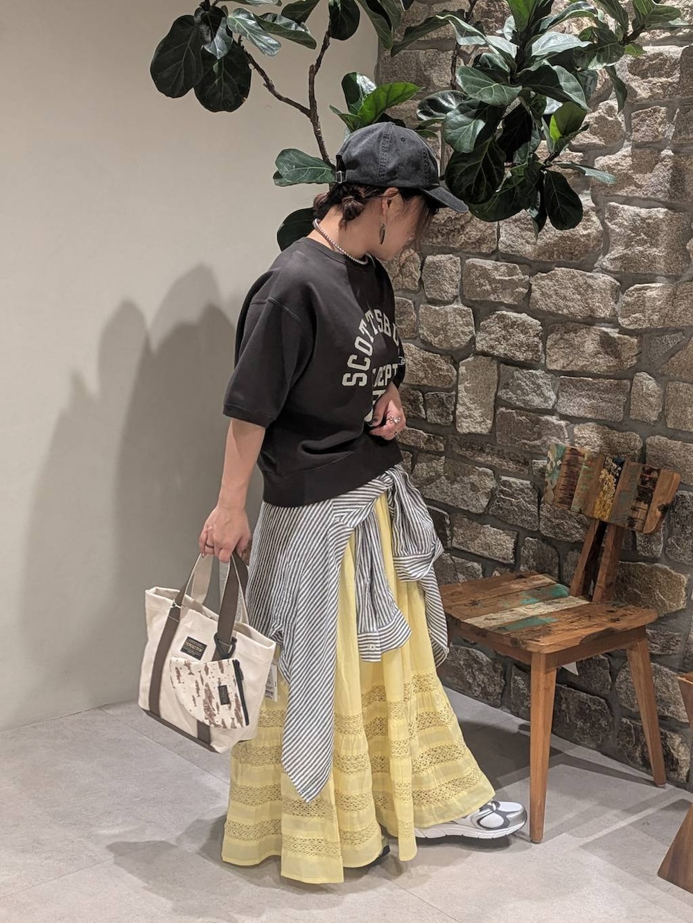 グレー系のスニーカー、ブラック系のTシャツ/カットソー、ベージュ系のトートバッグを着用したレディースの春コーディネートの2枚目の写真