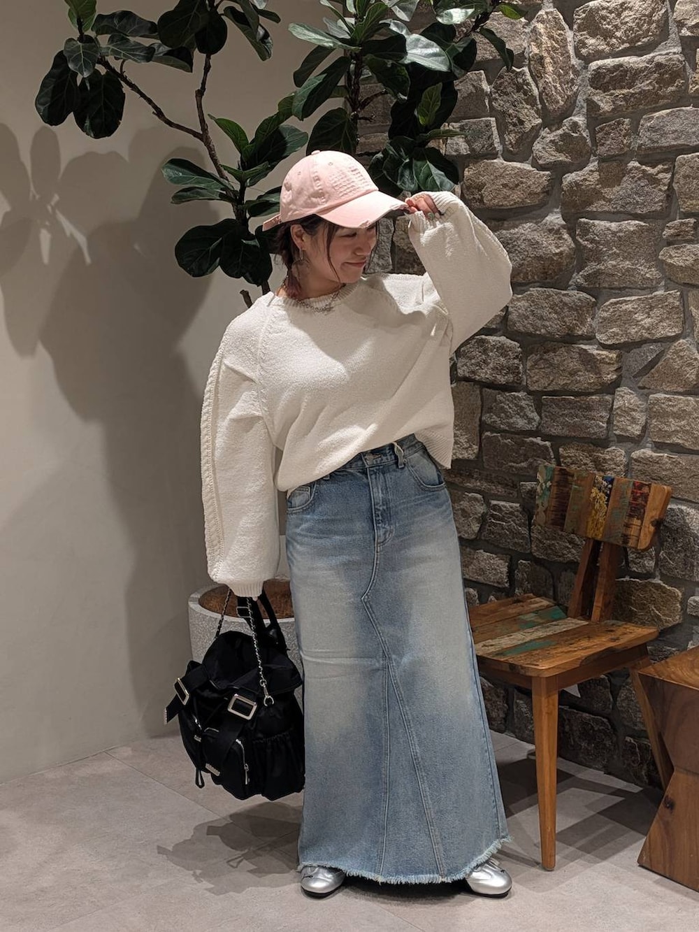 グレー系のスニーカー、ブルー系のデニムスカート、ブラック系のバックパック/リュックを着用したレディースの冬コーディネートの2枚目の写真