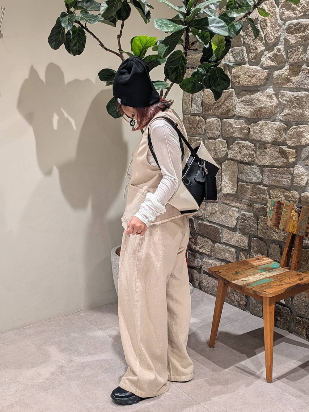 ブラック系のハンドバッグ、ブラック系のスニーカー、ベージュ系のベストを着用したレディースの春コーディネートの2枚目の写真