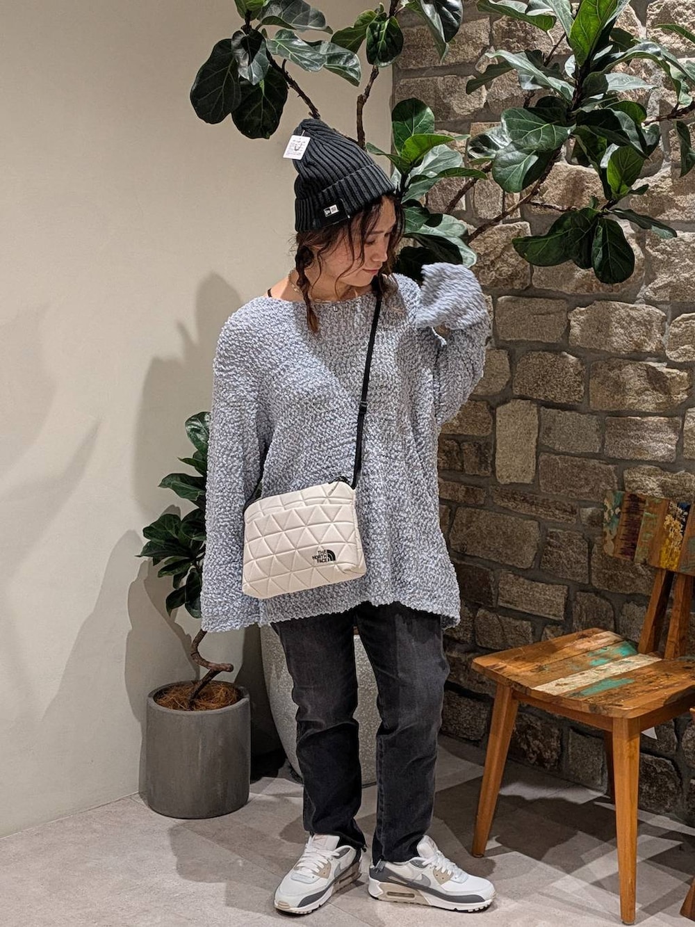 ブルー系のニット/セーター、ベージュ系のショルダーバッグ、グレー系のデニムパンツを着用したレディースの夏コーディネートの2枚目の写真