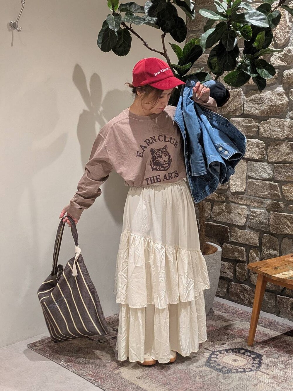 ブラウン系のトートバッグ、ブラウン系のTシャツ/カットソー、ブルー系のデニムジャケットを着用したレディースの秋コーディネートの3枚目の写真