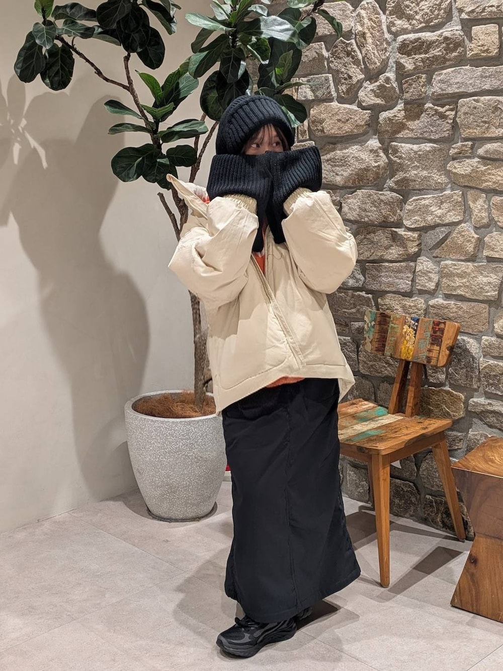 ブラック系のスカート、オレンジ系のニット/セーター、ホワイト系のダウンジャケット/コートを着用したレディースの冬コーディネートの2枚目の写真