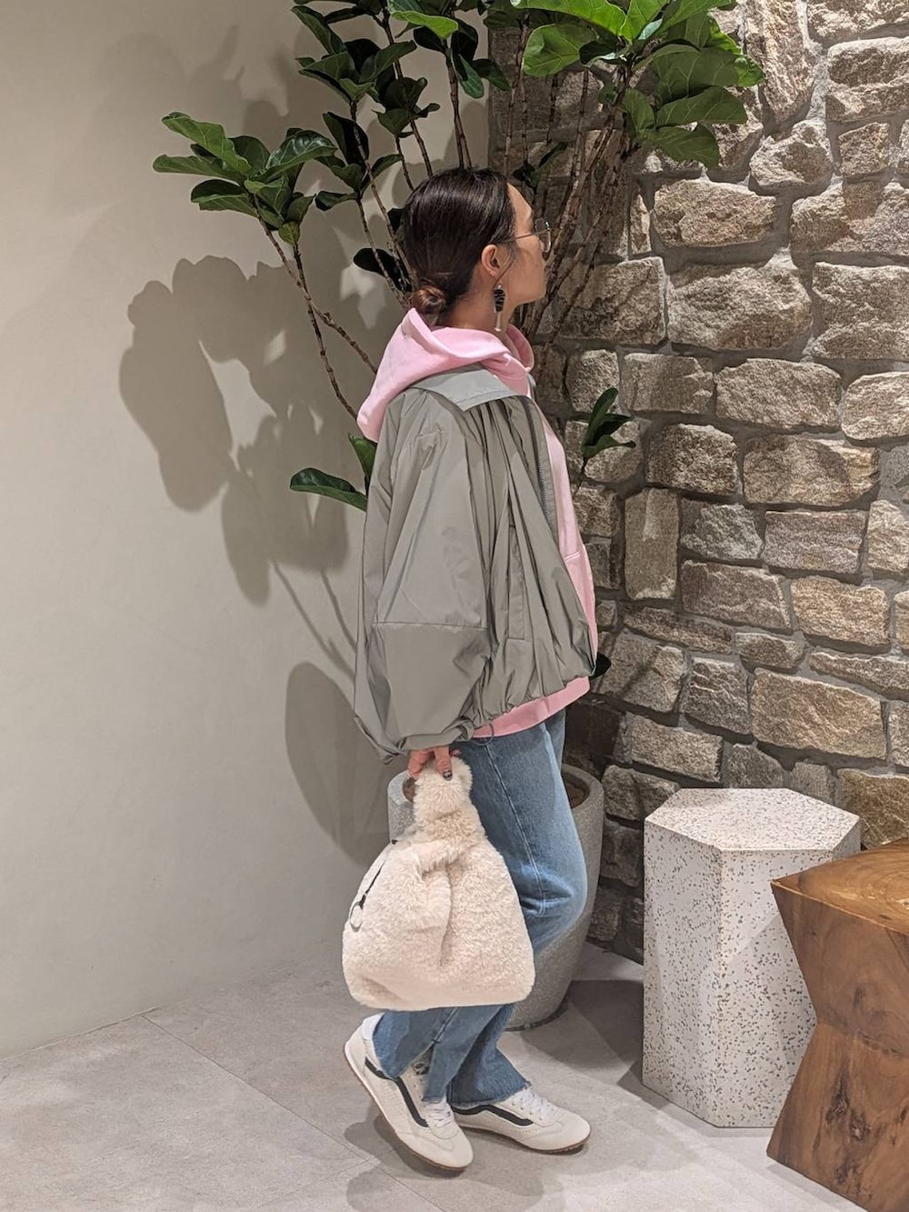 ベージュ系のハンドバッグ、ブルー系のデニムパンツ、ホワイト系のスニーカーを着用したレディースの秋コーディネートの2枚目の写真