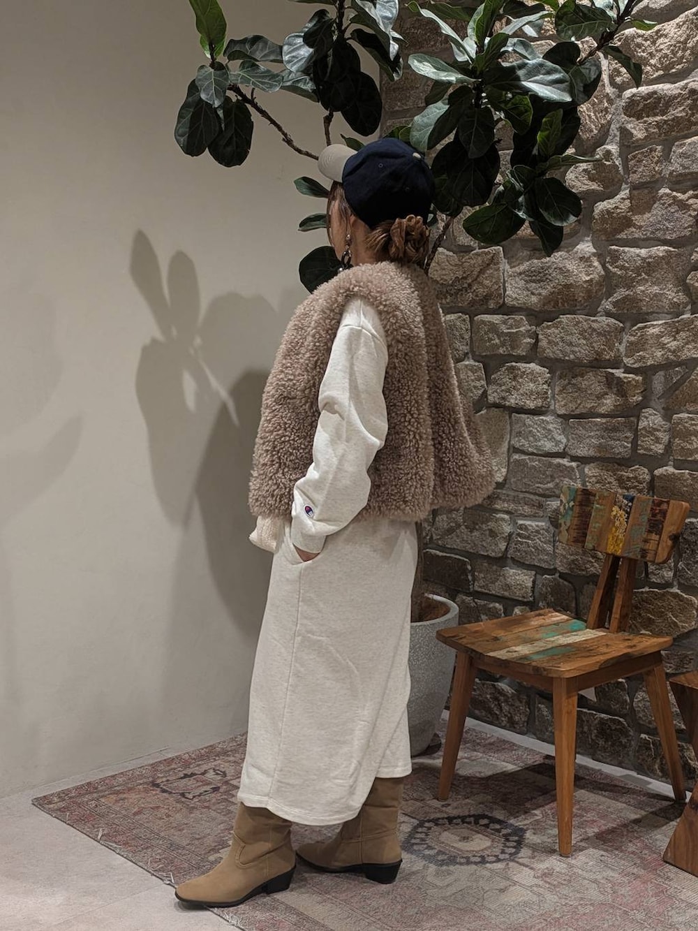 ベージュ系のブーツ、ブラウン系のベスト、ホワイト系のトートバッグを着用したレディースの秋コーディネートの2枚目の写真