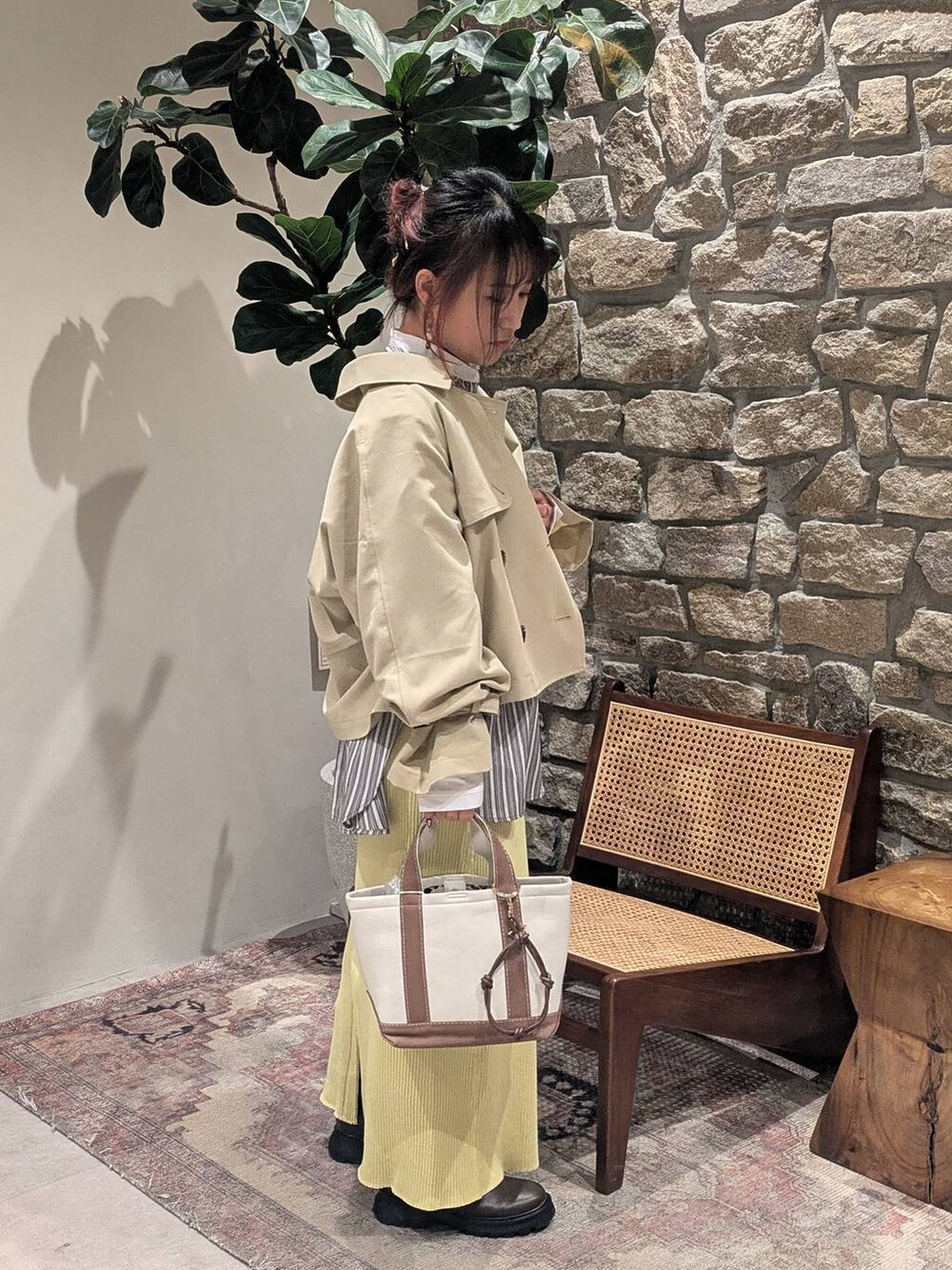 ブラウン系のブーツ、ベージュ系のトレンチコート、ブラウン系のトートバッグを着用したレディースの冬コーディネートの3枚目の写真