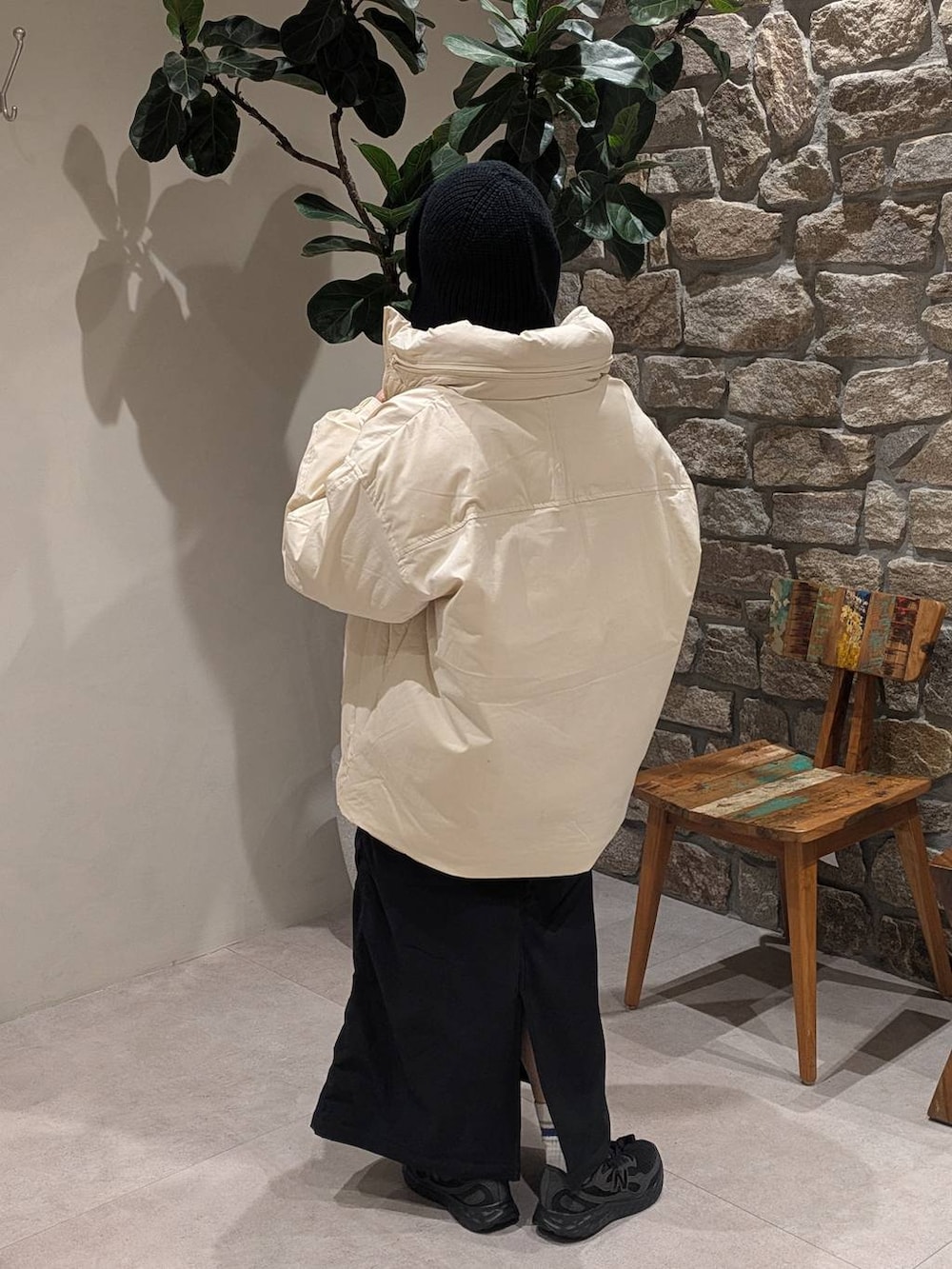 ブラック系のスカート、オレンジ系のニット/セーター、ホワイト系のダウンジャケット/コートを着用したレディースの冬コーディネートの3枚目の写真