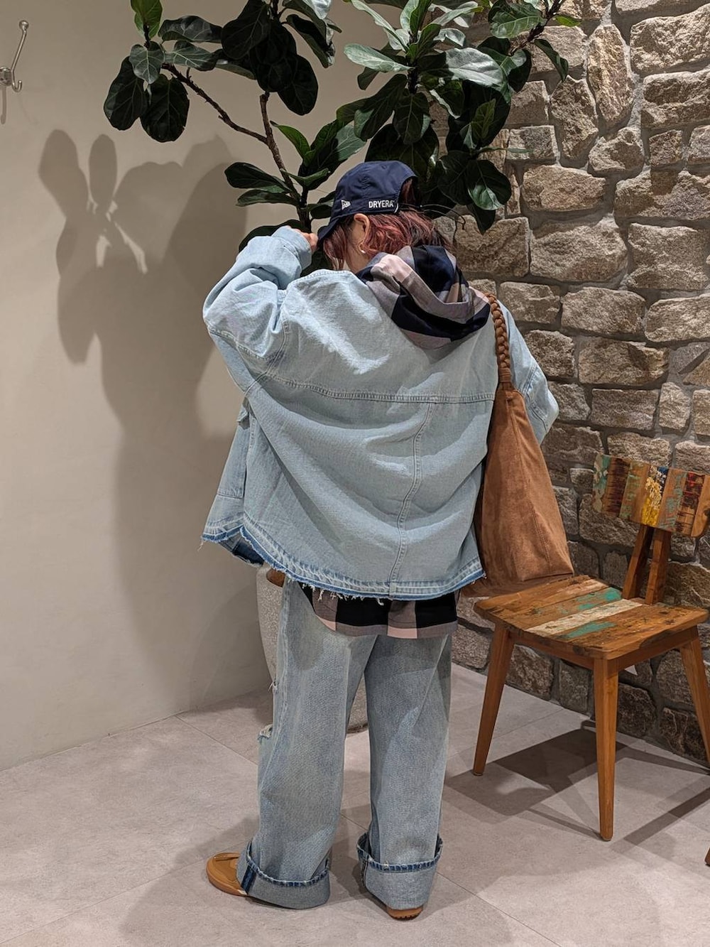 ブラウン系のトートバッグ、ブルー系のデニムパンツ、ブルー系のシャツ/ブラウスを着用したレディースの冬コーディネートの2枚目の写真