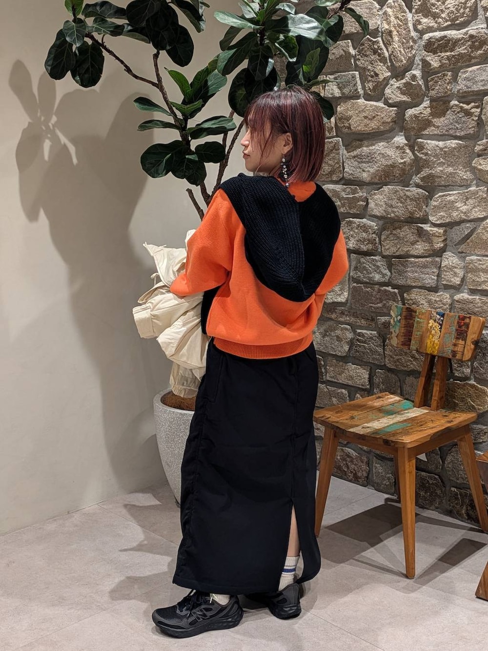 ブラック系のスカート、オレンジ系のニット/セーター、ホワイト系のダウンジャケット/コートを着用したレディースの冬コーディネートの6枚目の写真