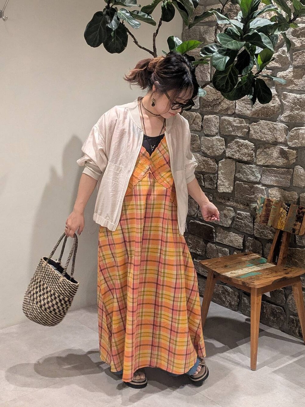 ブラック系のかごバッグ、ブルー系のデニムパンツ、ベージュ系のサンダルを着用したレディースの春コーディネートの2枚目の写真