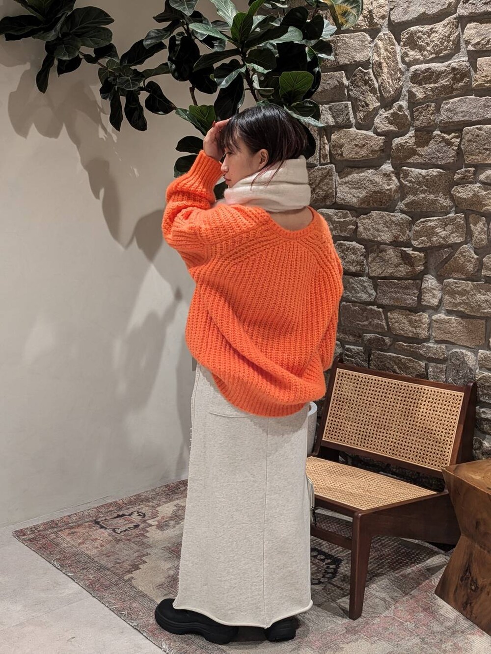 グレー系のショルダーバッグ、ブラック系のブーツ、オレンジ系のニット/セーターを着用したレディースの冬コーディネートの2枚目の写真