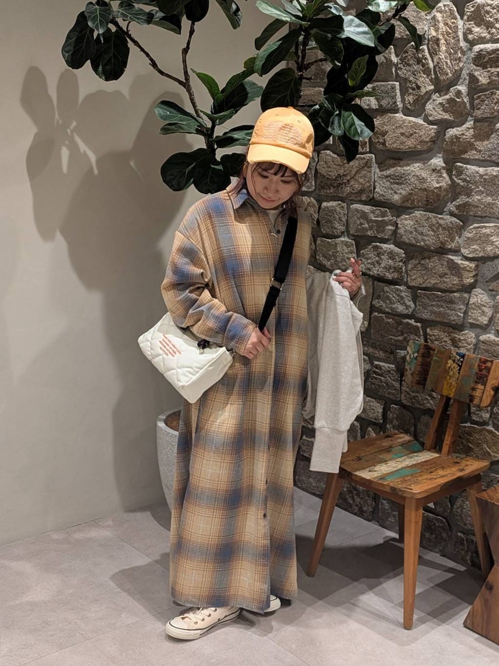 ホワイト系のスニーカー、イエロー系のシャツワンピース、ホワイト系のショルダーバッグを着用したレディースの冬コーディネートの4枚目の写真