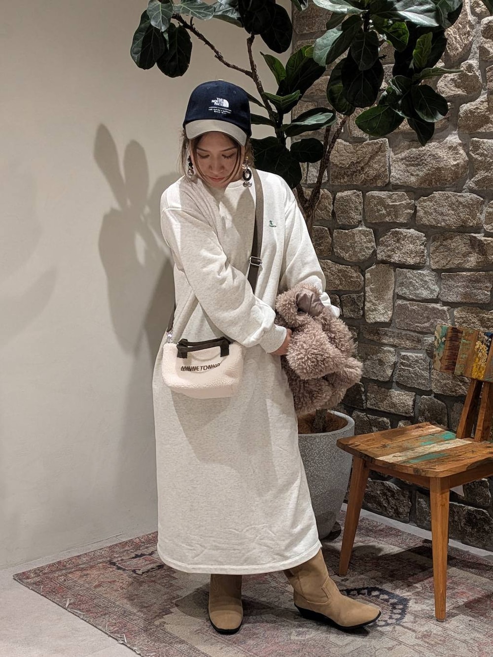 ベージュ系のブーツ、ブラウン系のベスト、ホワイト系のトートバッグを着用したレディースの秋コーディネートの4枚目の写真