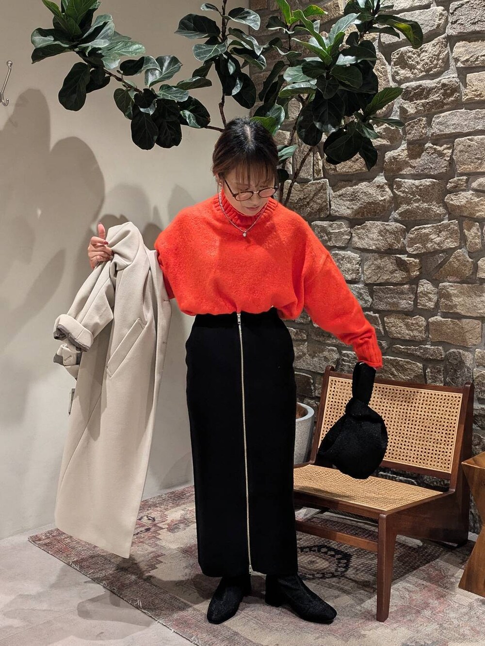 ブラック系のブーツ、オレンジ系のニット/セーター、ブルー系のハンドバッグを着用したレディースの秋コーディネートの2枚目の写真