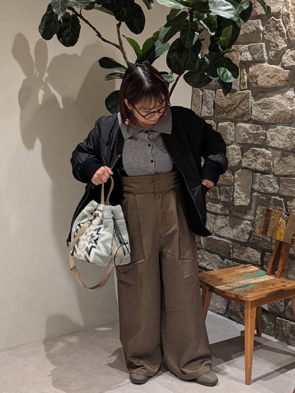 ブラウン系のスニーカー、グレー系のハンドバッグ、ブラック系のブルゾンを着用したレディースの冬コーディネートの4枚目の写真