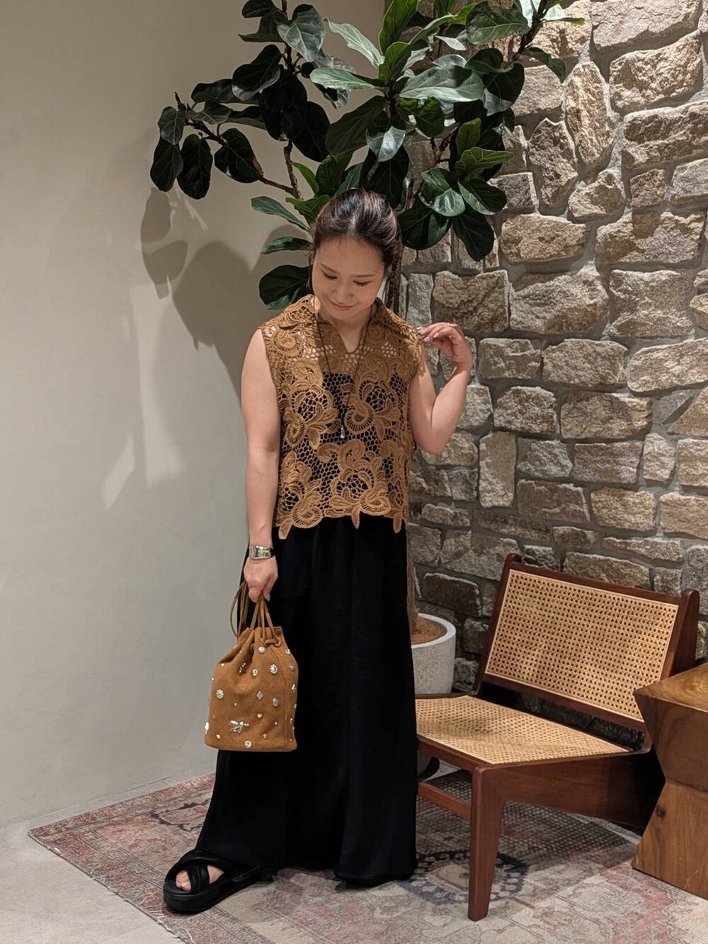 ブラック系のスカート、イエロー系のベスト、シルバー系のネックレスを着用したレディースの夏コーディネートの2枚目の写真