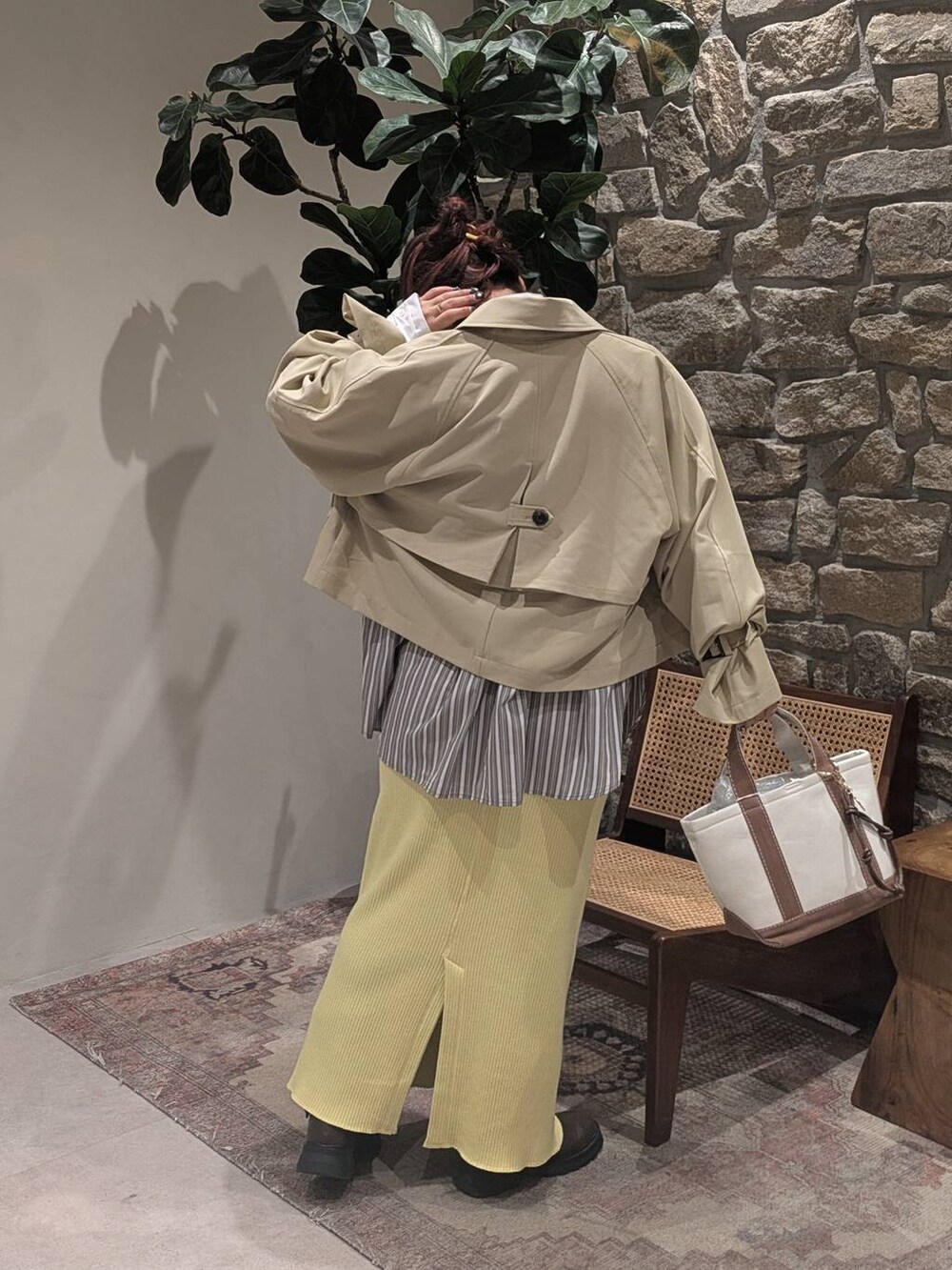 ブラウン系のブーツ、ベージュ系のトレンチコート、ブラウン系のトートバッグを着用したレディースの冬コーディネートの4枚目の写真