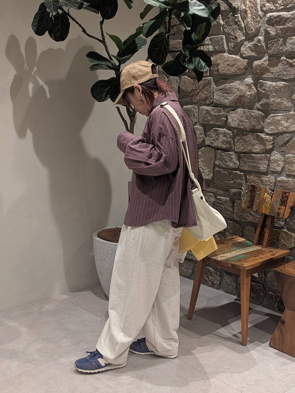 ブルー系のスニーカー、ブラウン系のシャツ/ブラウス、ホワイト系のショルダーバッグを着用したレディースの冬コーディネートの4枚目の写真