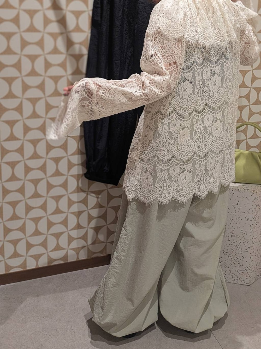 グリーン系のハンドバッグ、ホワイト系のローファー、グレー系のその他パンツを着用したレディースの冬コーディネートの3枚目の写真