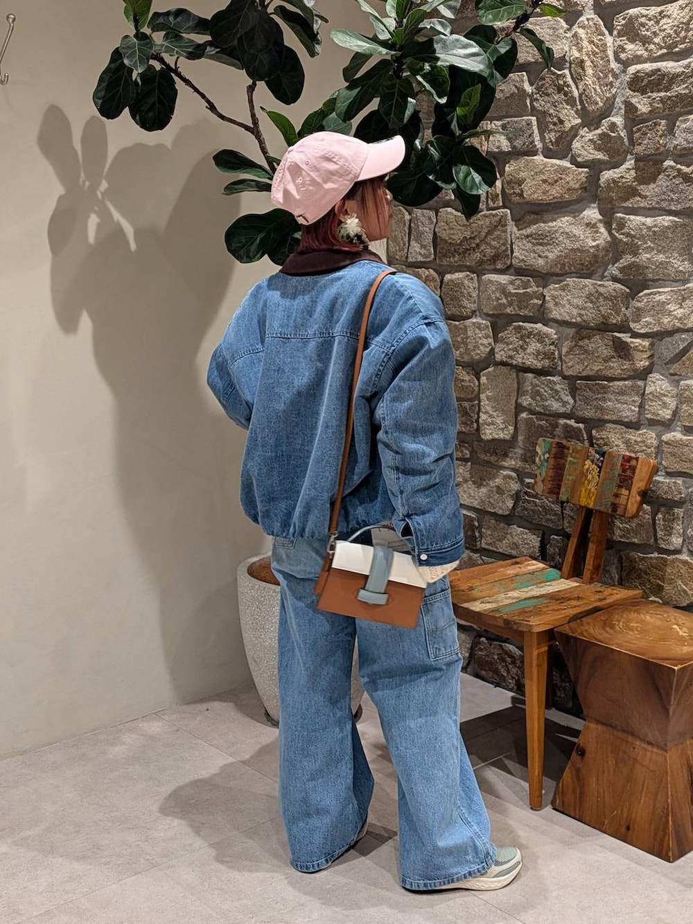 グレー系のスニーカー、ブラウン系のショルダーバッグ、ブルー系のデニムパンツを着用したレディースの冬コーディネートの6枚目の写真