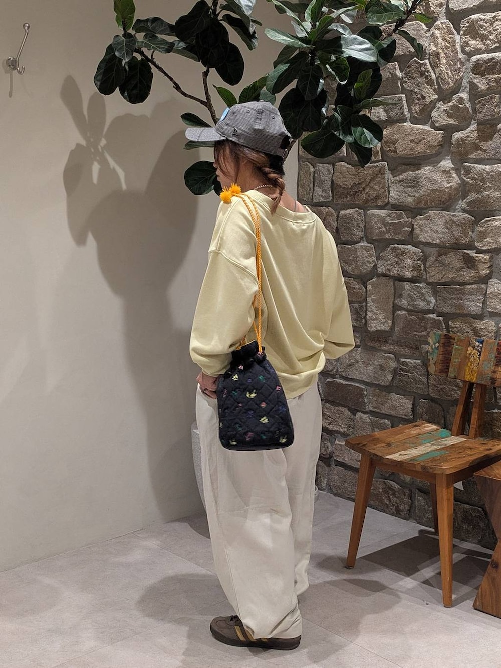 ブラウン系のスニーカー、ブラック系のハンドバッグ、イエロー系のスウェットを着用したレディースの秋コーディネートの3枚目の写真