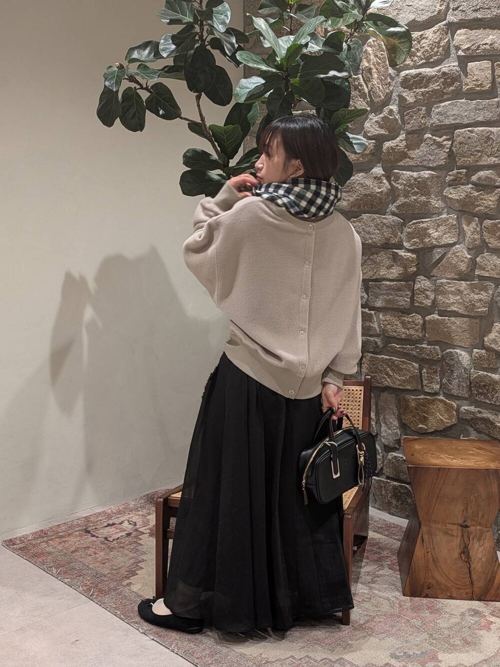 ブラック系のスカート、ブラック系のショルダーバッグ、ベージュ系のカーディガン/ボレロを着用したレディースの冬コーディネートの2枚目の写真
