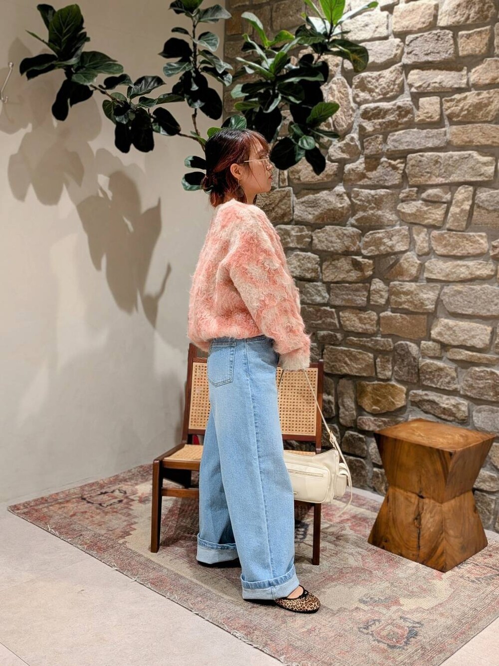 ホワイト系のハンドバッグ、ブルー系のデニムパンツ、ベージュ系のニット/セーターを着用したレディースの冬コーディネートの2枚目の写真