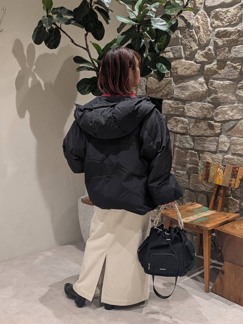 ベージュ系のスカート、ブラック系のブーツ、ブラック系のハンドバッグを着用したレディースの冬コーディネートの2枚目の写真