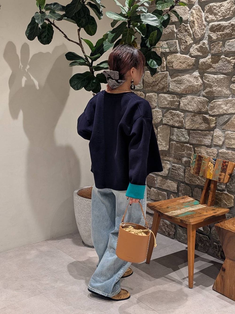 イエロー系のハンドバッグ、ブルー系のデニムパンツ、ベージュ系のローファーを着用したレディースの冬コーディネートの3枚目の写真