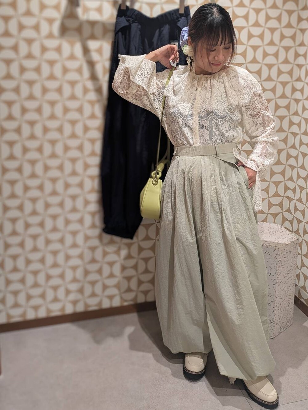 グリーン系のハンドバッグ、ホワイト系のローファー、グレー系のその他パンツを着用したレディースの冬コーディネートの7枚目の写真