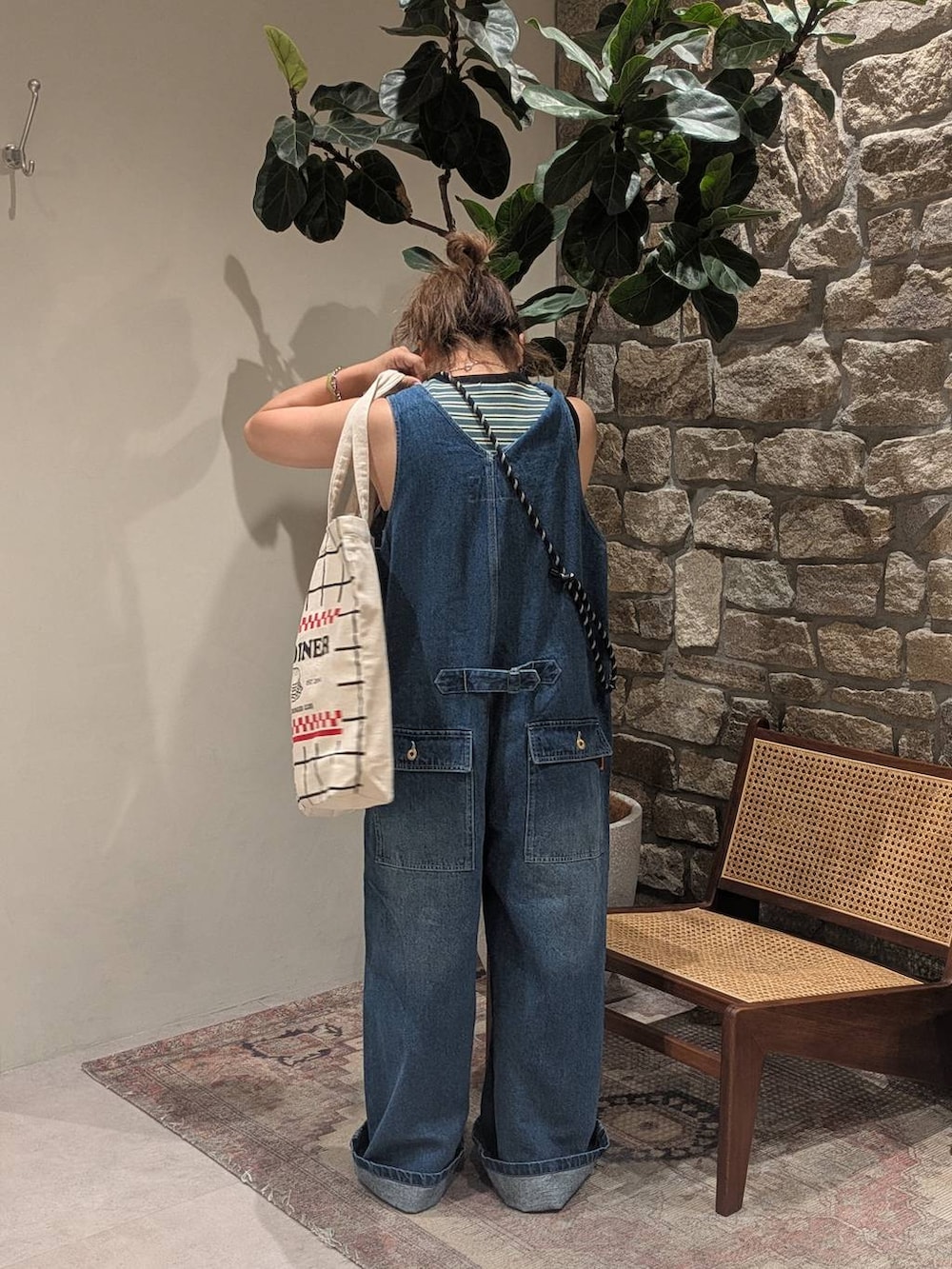 ブラック系のトートバッグ、ベージュ系のスニーカー、グリーン系のTシャツ/カットソーを着用したレディースの夏コーディネートの4枚目の写真