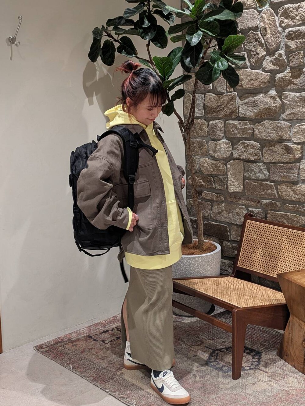 グリーン系のスカート、イエロー系のパーカー、グリーン系のカバーオールを着用したレディースの冬コーディネートの2枚目の写真