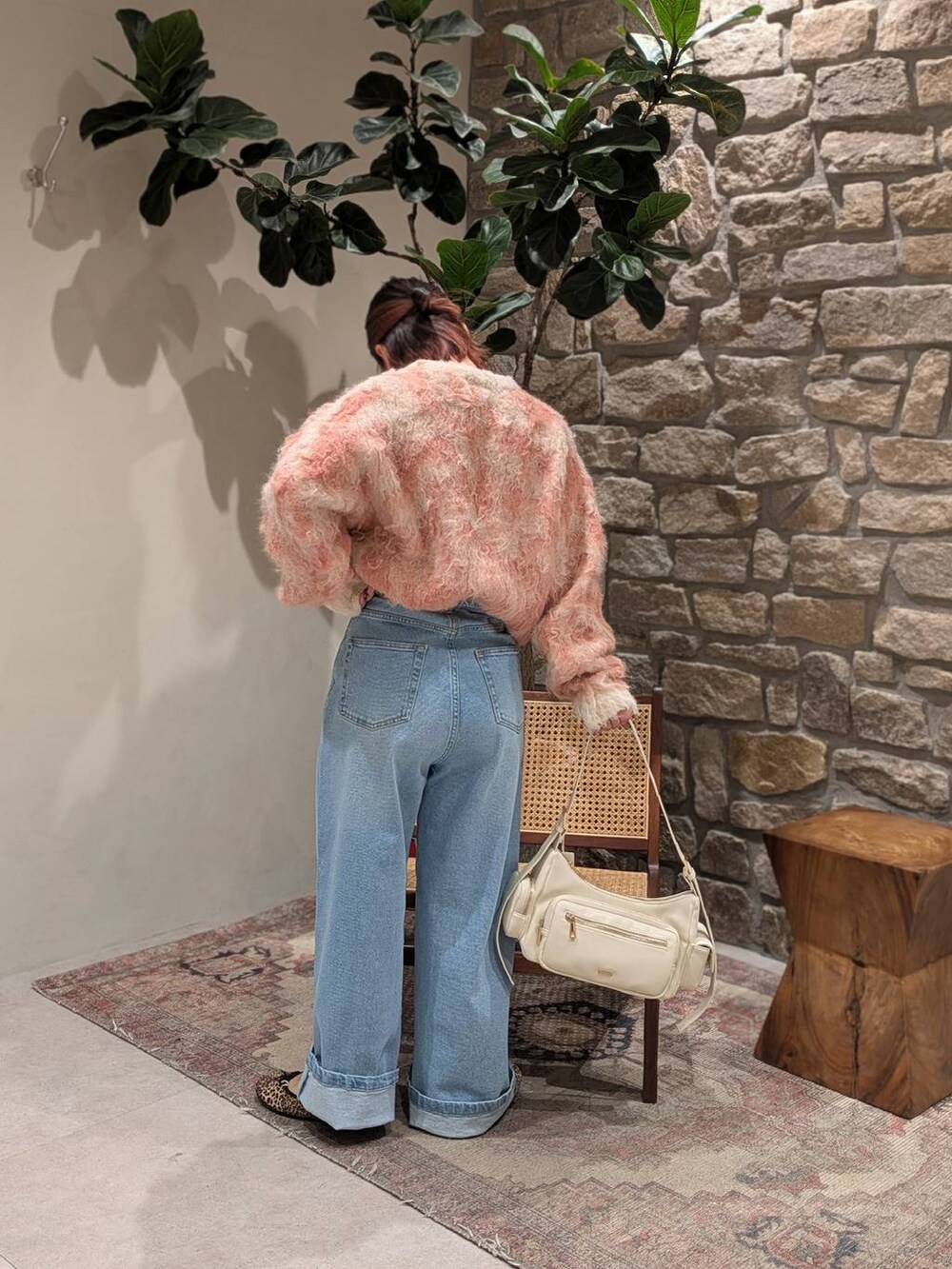 ホワイト系のハンドバッグ、ブルー系のデニムパンツ、ベージュ系のニット/セーターを着用したレディースの冬コーディネートの3枚目の写真