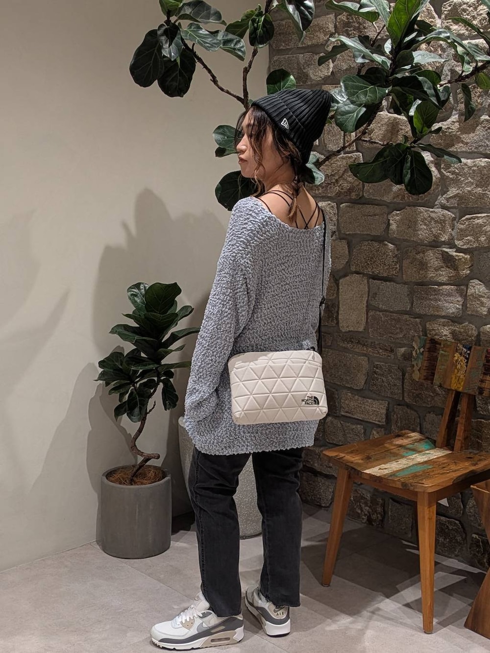 ブルー系のニット/セーター、ベージュ系のショルダーバッグ、グレー系のデニムパンツを着用したレディースの夏コーディネートの3枚目の写真