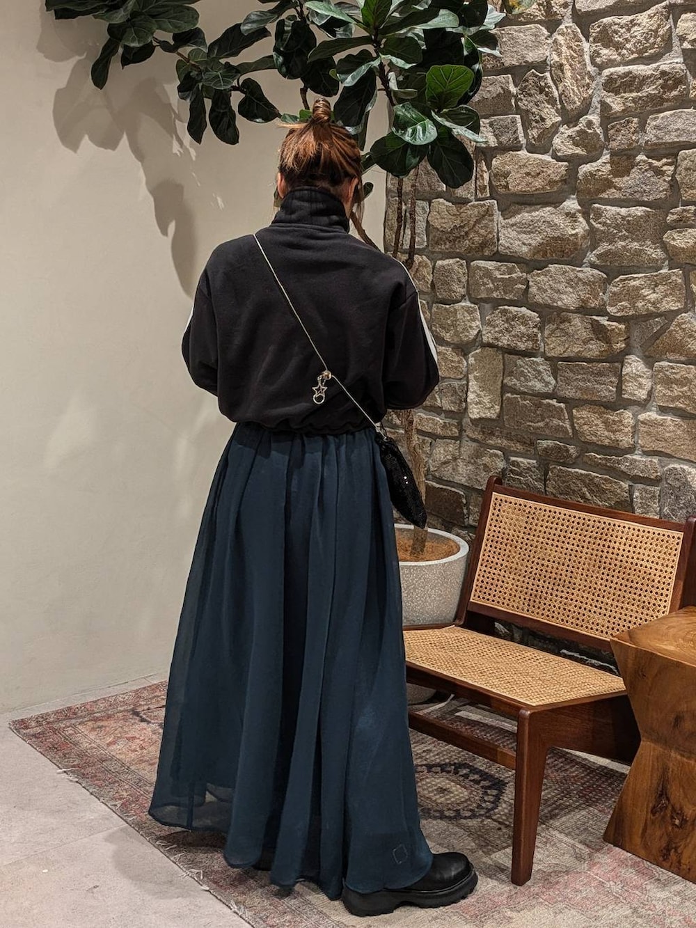 ブラック系のショルダーバッグ、ブラック系のブーツ、ブルー系のスカートを着用したレディースの秋コーディネートの2枚目の写真