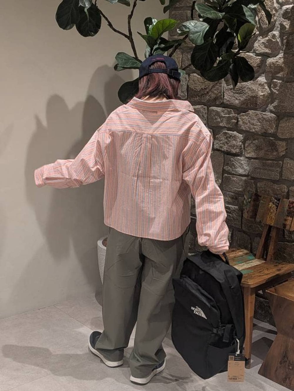 ブルー系のスニーカー、オレンジ系のシャツ/ブラウス、ブラック系のバックパック/リュックを着用したレディースの春コーディネートの4枚目の写真