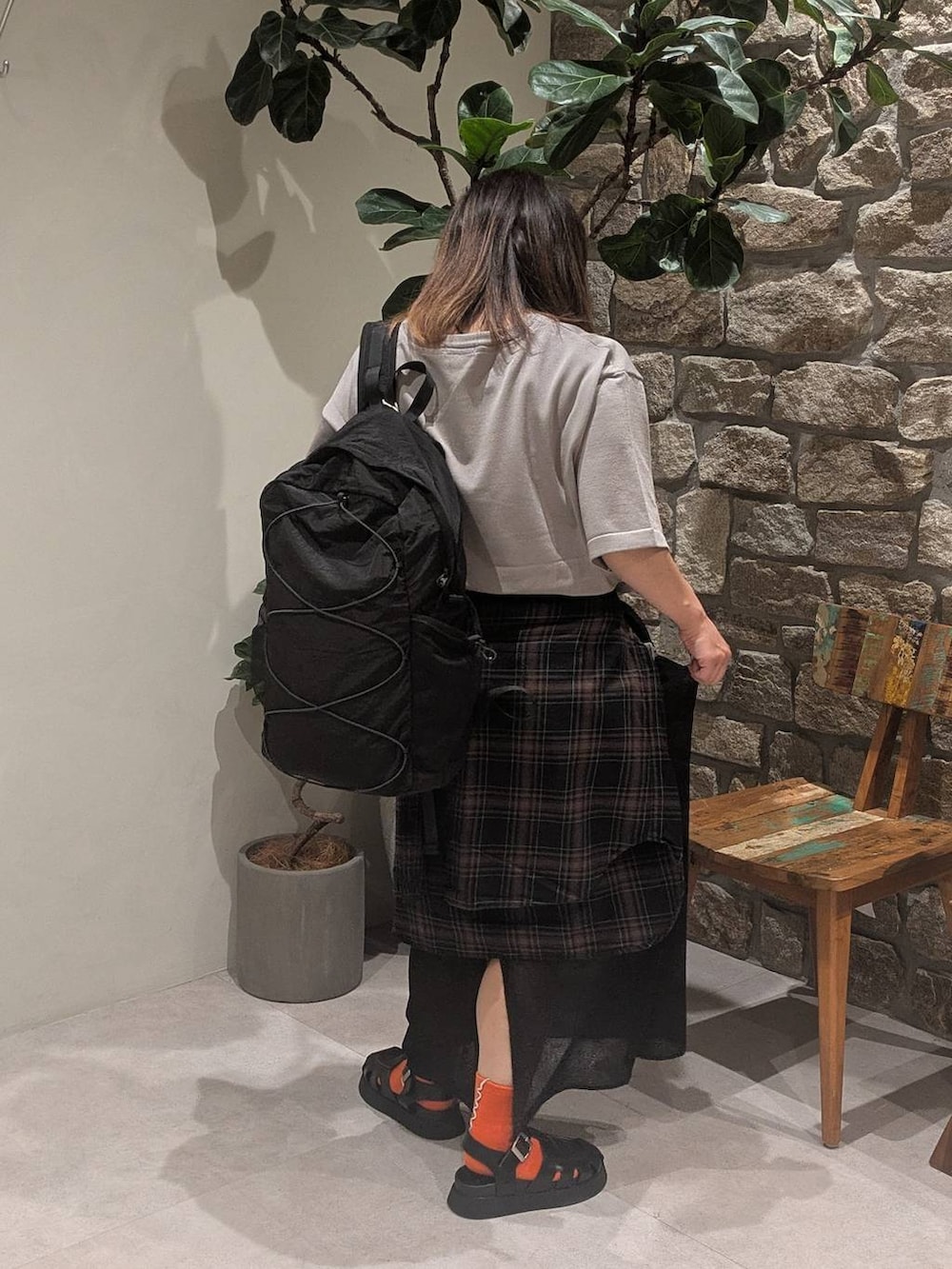 ブラック系のスカート、ブラック系のバックパック/リュック、グレー系のニット/セーターを着用したレディースの夏コーディネートの3枚目の写真