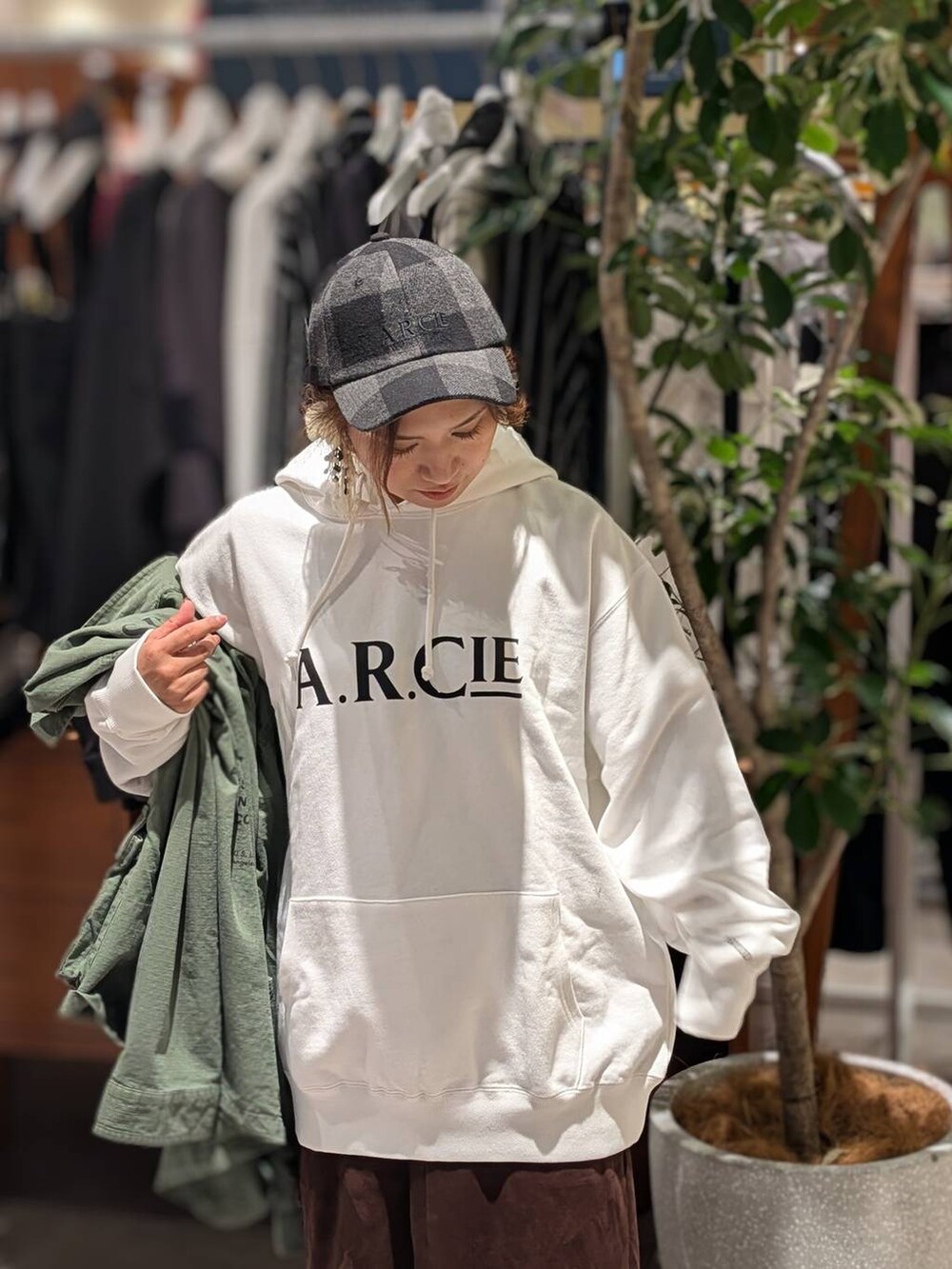 ホワイト系のパーカー、ブラウン系のスカート、ブルー系のトートバッグを着用したレディースの秋コーディネートの2枚目の写真