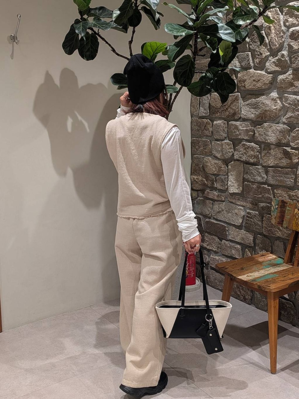 ブラック系のハンドバッグ、ブラック系のスニーカー、ベージュ系のベストを着用したレディースの春コーディネートの3枚目の写真