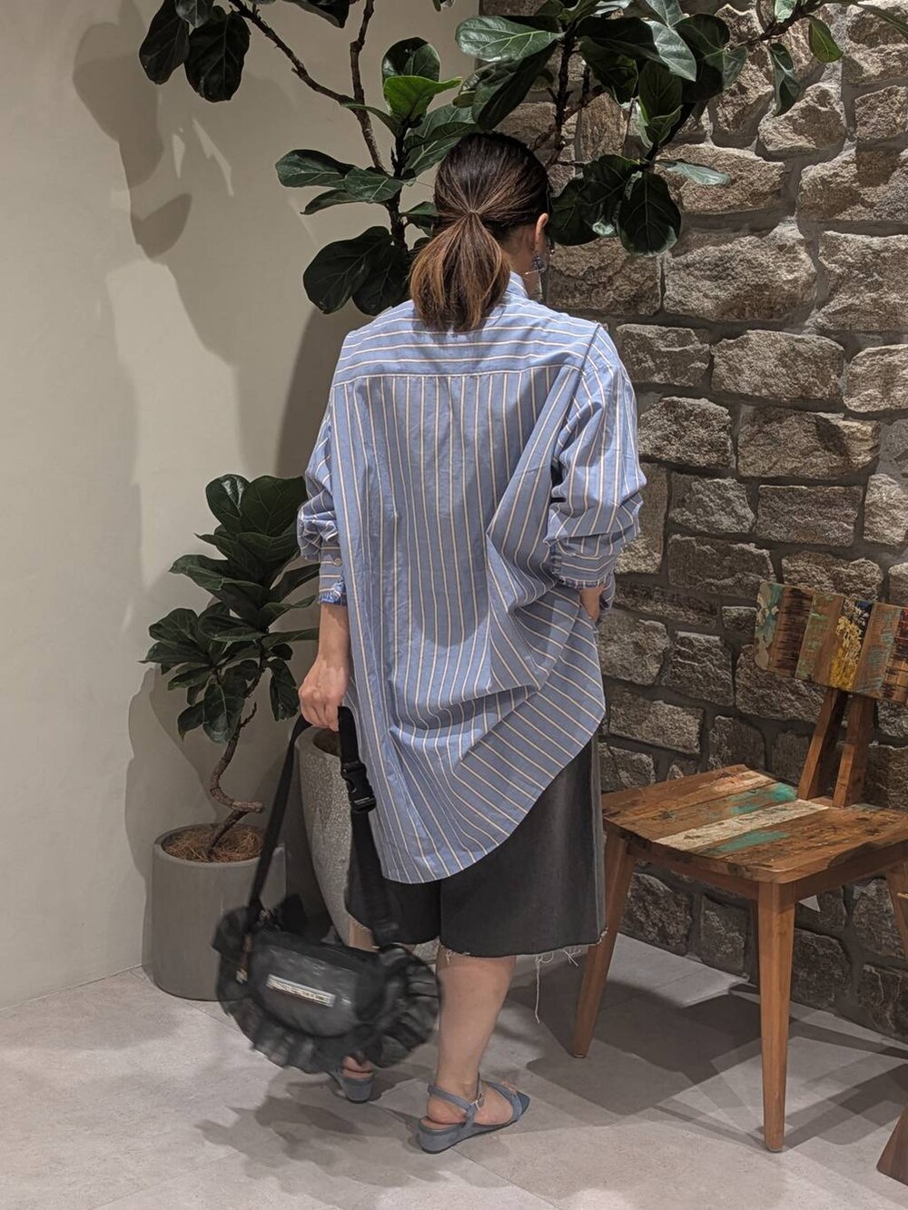 ブルー系のチュニック、ブルー系のサンダル、ブラック系のショルダーバッグを着用したレディースの夏コーディネートの4枚目の写真