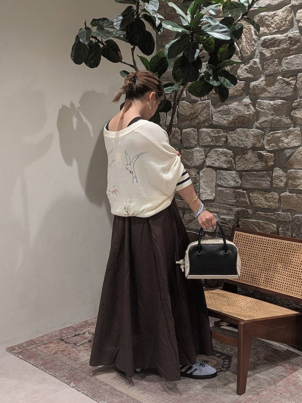 ブルー系のスニーカー、ブラック系のハンドバッグ、ホワイト系のニット/セーターを着用したレディースの夏コーディネートの2枚目の写真