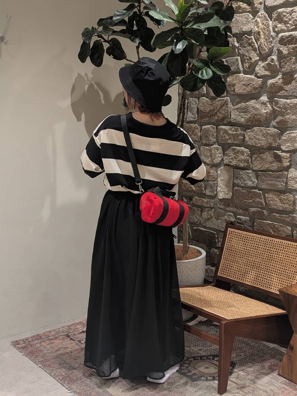 ブラック系のニット/セーター、レッド系のショルダーバッグ、ブラック系のスカートを着用したレディースの春コーディネートの2枚目の写真