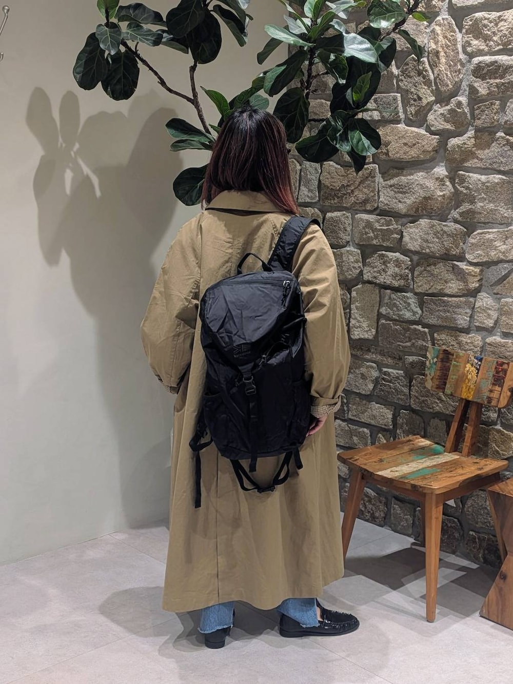 ブルー系のデニムパンツ、ブラック系のローファー、イエロー系のステンカラーコートを着用したレディースの冬コーディネートの2枚目の写真