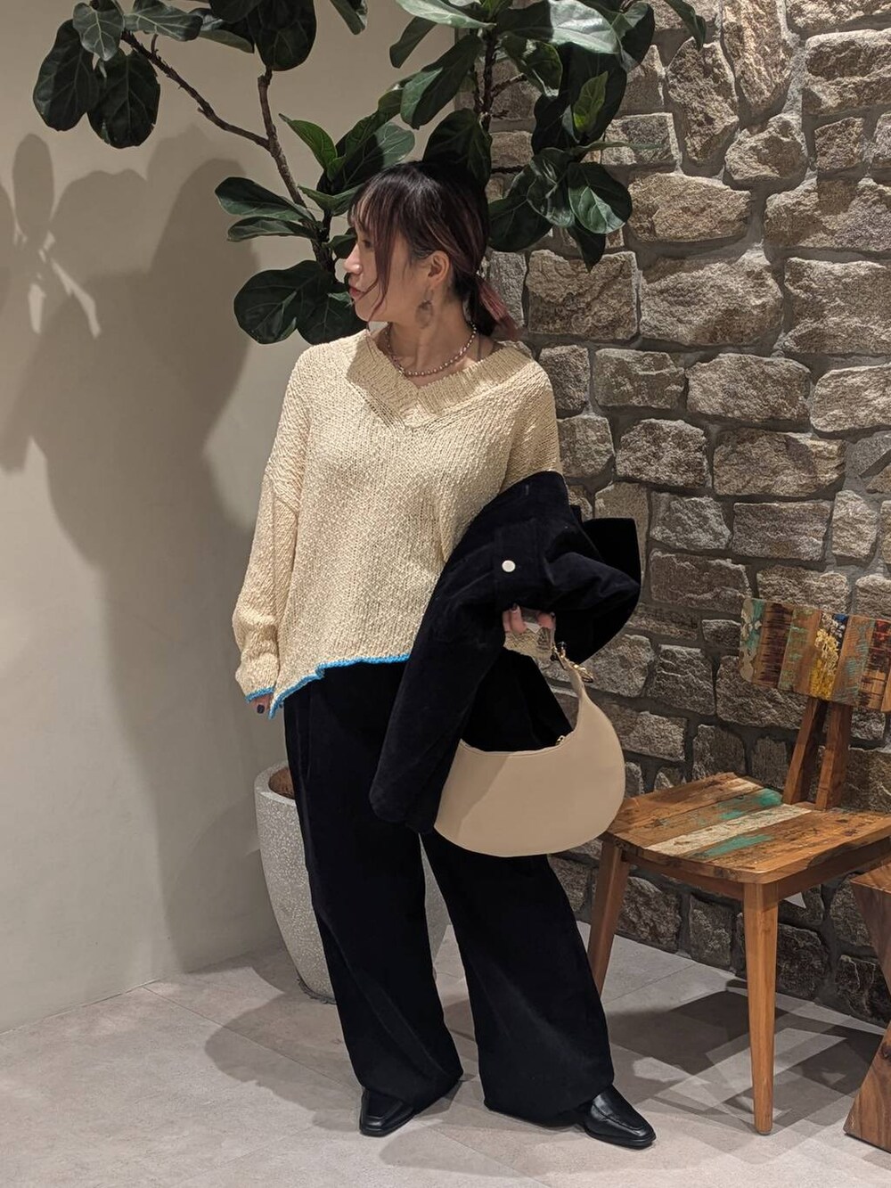 ベージュ系のハンドバッグ、ブラック系のブーツ、ホワイト系のニット/セーターを着用したレディースの冬コーディネートの3枚目の写真