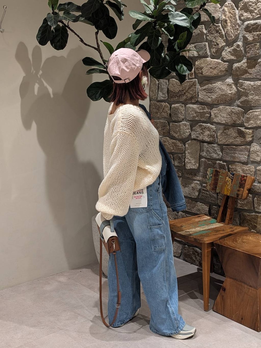 グレー系のスニーカー、ブラウン系のショルダーバッグ、ブルー系のデニムパンツを着用したレディースの冬コーディネートの3枚目の写真