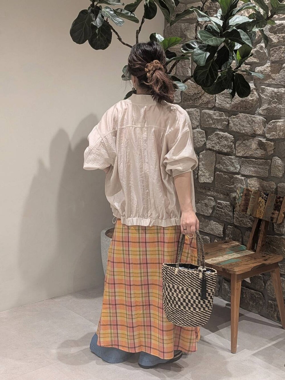 ブラック系のかごバッグ、ブルー系のデニムパンツ、ベージュ系のサンダルを着用したレディースの春コーディネートの4枚目の写真