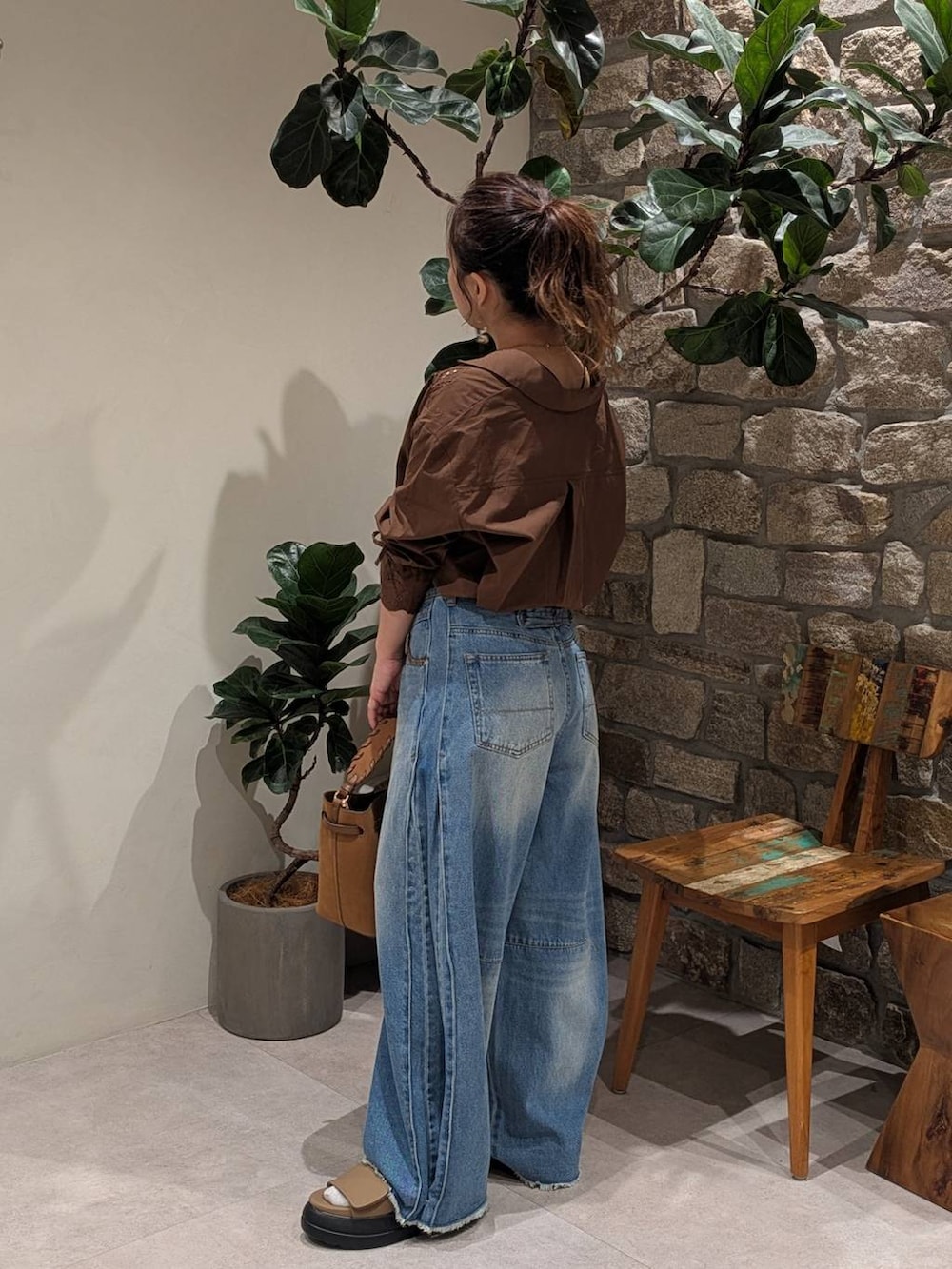 ブルー系のデニムパンツ、ブラウン系のサンダル、イエロー系のショルダーバッグを着用したレディースの夏コーディネートの2枚目の写真