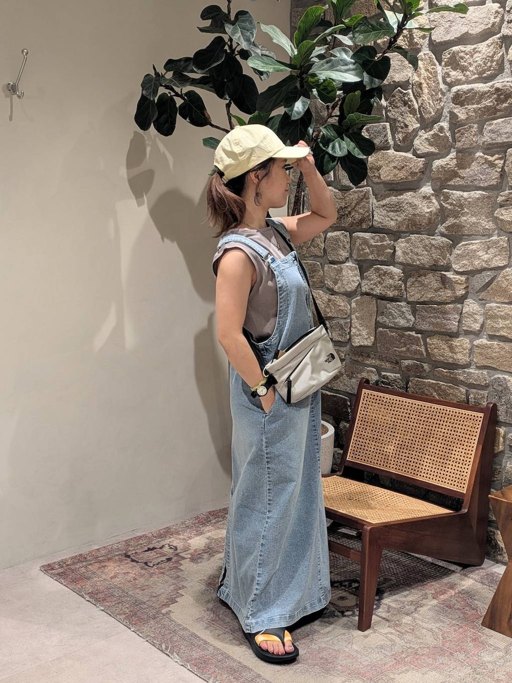 ブラック系のサンダル、ブルー系のジャンパースカート、ブラウン系のTシャツ/カットソーを着用したレディースの夏コーディネートの2枚目の写真